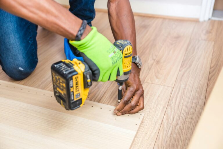 Handyman using a power drill on a wooden floor in Hamilton