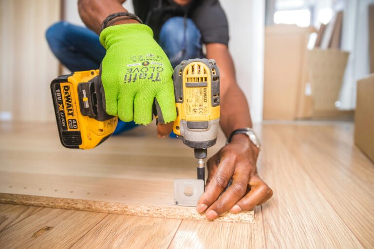 Handyman using a power drill on a wooden floor in Hamilton